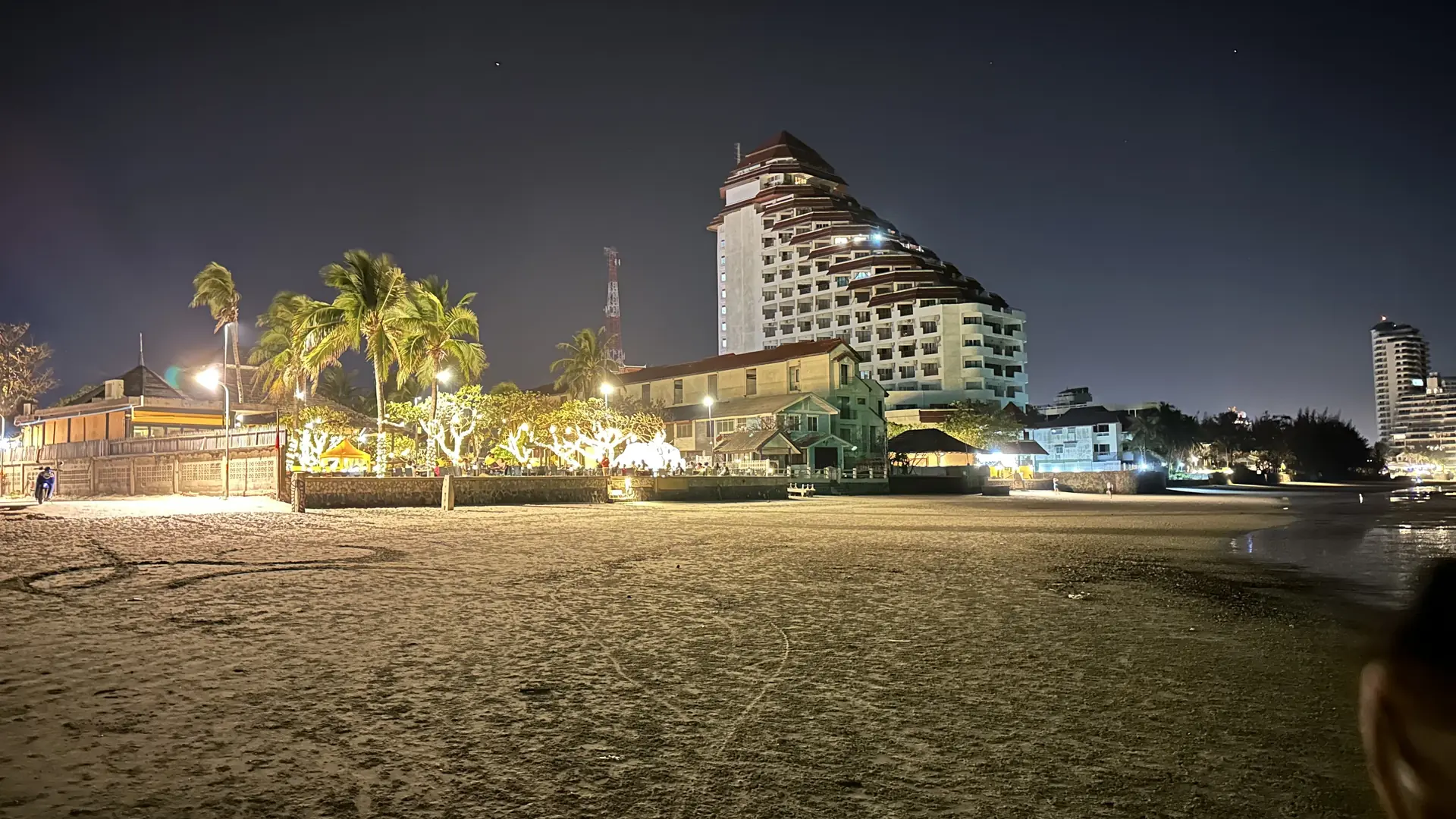 Beachfront restaurants lit up along the sand at night
